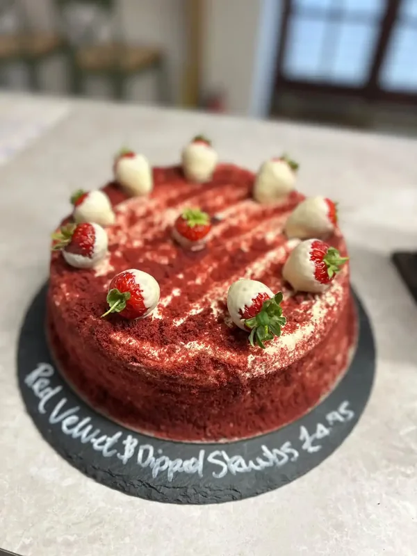 Homemade Red Velvet cake topped with white chocolate dipped strawberries on the counter at Calon
